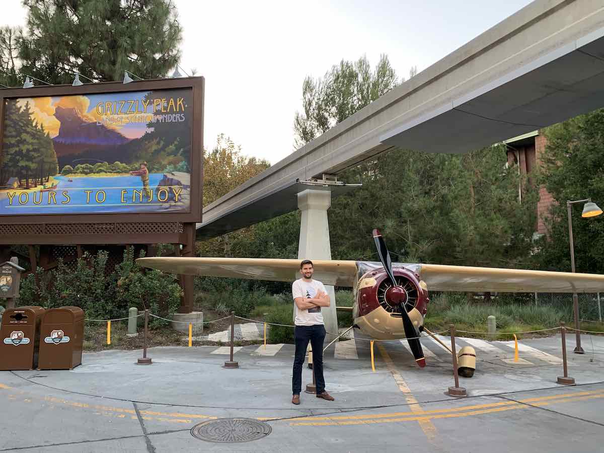Angelo Genasci standing infant of a plane in Disney's California Adventure Park